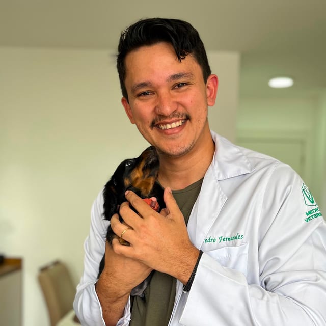 Dr. Pedro Fernandes, de jaleco, segurando um filhote de dachshund