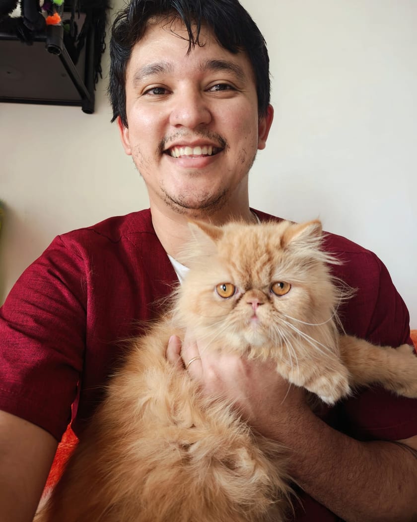 Dr. Pedro Fernandes sorrindo com um gato persa no colo